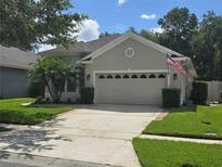 Charming single-story home with a manicured lawn, complemented by a beige exterior and a two-car garage at 148 Peregrine Ct, Winter Springs, FL 32708