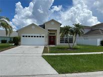 Charming home with a well-maintained lawn, palm trees, a two-car garage, and a vibrant red front door at 2149 Mallard Creek Cir, Kissimmee, FL 34743