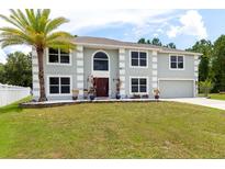 Charming two-story home with a palm tree, green lawn, and well manicured landscaping at 4064 Sunny Day Way, Kissimmee, FL 34744