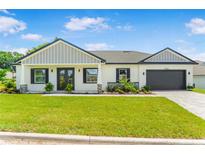 Charming single-story home with a well-manicured lawn, dark shutters, and an attached two-car garage at 1006 Linkside Ct, Apopka, FL 32712