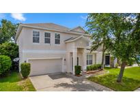 Two-story home featuring an attached garage, well-maintained landscaping, and neutral exterior paint at 10299 Cypress Knee Cir, Orlando, FL 32825