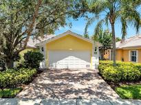 Charming home featuring a white two-car garage, beautiful landscaping, and a brick driveway at 11854 Delfina Ln, Orlando, FL 32827