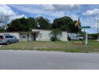 Cozy single-story home featuring a well-maintained lawn and mature trees at 1256 N Pine Hills Rd, Orlando, FL 32808