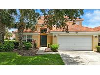 Charming home with a red tile roof, lush landscaping, and an attached two-car garage at 255 Cordova Ave, Davenport, FL 33897