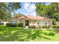 Inviting single-story home with a well-maintained lawn, mature trees, and manicured landscaping at 2613 Breezy Meadow Rd, Apopka, FL 32712