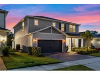 Charming two-story home with a well-manicured lawn and a two-car garage under a colorful dusk sky at 4316 Foggy Oak Ln, Sanford, FL 32773
