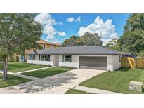 Well-maintained home with a lush green lawn, a dark grey roof, and a two-car garage at 5882 Marlberry Dr, Orlando, FL 32819