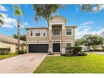 Two-story home features a dark garage door, manicured lawn, and brick paver driveway on a sunny day at 9067 Stonebury Way, Orlando, FL 32832