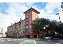 Attractive condo building exterior with balconies, colorful facade, palm trees and street view on a sunny day at 911 N Orange Ave # 143, Orlando, FL 32801