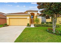 Inviting yellow home with a well-manicured lawn and a two-car garage at 1041 Cherry Valley Way, Orlando, FL 32828