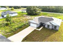 Charming gray home boasts a long driveway, attached garage, and a freshly seeded lawn at 1304 Hillsborough Ct, Kissimmee, FL 34759