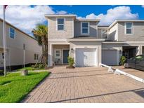 Two-story townhouse featuring a one car garage, nicely landscaped yard, and a brick driveway at 2596 Penguin Blvd, Davenport, FL 33837