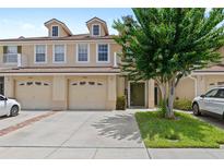 Inviting townhome featuring a well-maintained lawn, two-car garage, and charming architectural details at 3055 Ashland N Ln, Kissimmee, FL 34741