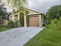 Charming one-story home with a well-manicured lawn and a two-car garage and palm tree at 679 Midori St, Orlando, FL 32811