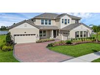 Beautiful two-story home with a brick driveway, two-car garage, manicured landscaping, and beige stucco exterior at 10117 Atwater Bay Dr, Winter Garden, FL 34787