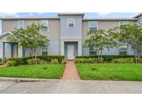 Charming two-story townhome with a well-maintained lawn, decorative shrubbery, and a brick path leading to the front door at 141 Claire Ln, Davenport, FL 33837