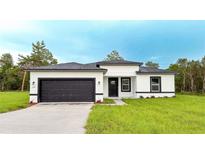Modern home with a dark garage door, black framed windows, and a well-manicured lawn at 15621 Sw 37Th Cir, Ocala, FL 34473