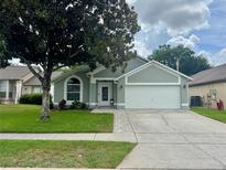 Charming single-story home with a well-manicured lawn, mature tree, and an attached two-car garage at 1659 Canton Ln, Oviedo, FL 32765