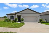 Charming one-story home with well-manicured lawn and a two-car garage on a sunny day at 311 Eaglecrest Dr, Haines City, FL 33844