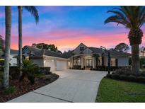 Stunning home exterior with a well-manicured lawn, mature palm trees, and a circular driveway at sunset at 3267 Regal Crest Dr, Longwood, FL 32779