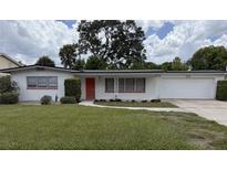 Charming single-story home featuring a well-maintained lawn, an attached garage, and a welcoming red front door at 3716 Neptune Dr, Orlando, FL 32804