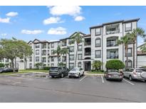 Beautiful multi-story condo building with white facade, dark trim, balconies, and lush tropical landscaping at 4114 Breakview Dr # 110, Orlando, FL 32819