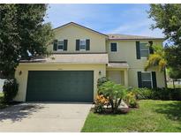 Two-story home with a well-manicured lawn, two-car garage, and dark green shutters at 4901 Stone Acres Cir, St Cloud, FL 34771