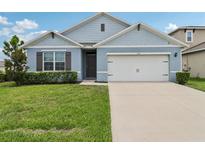 Charming single-story home with a well-manicured lawn and a two-car garage at 585 Talisi Loop, St Cloud, FL 34771