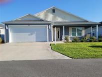 Charming single-story home featuring a two-car garage, well-manicured lawn, and cozy front porch at 744 Barron Pl, The Villages, FL 32163