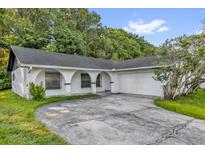 Charming single-story home featuring an arched portico and a spacious driveway leading to an attached garage at 1533 Ravana Dr, Orlando, FL 32822
