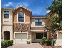 Charming two-story townhome featuring a stone facade, one-car garage, and nicely landscaped front yard at 1833 Portofino Meadows Blvd, Orlando, FL 32824