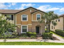 Inviting two-story townhome featuring a well-manicured lawn and a beautiful palm tree in the front yard at 1935 Majorca Dr, Kissimmee, FL 34747