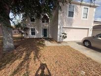 Two-story home featuring a front-facing two car garage, a lawn covered with leaves and a partial driveway at 266 Vervain Ave, Davenport, FL 33837