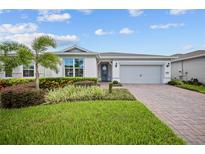 Beautiful one-story home with lush landscaping, brick-paved driveway, and an attached two-car garage at 2698 River Creek Ln, St Cloud, FL 34771