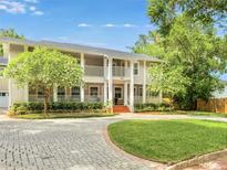 Inviting two-story home featuring a brick driveway, manicured lawn, and covered porch at 315 Desoto Cir, Orlando, FL 32804