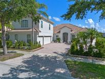 Charming white stucco home featuring a tile roof, manicured landscaping, and a brick-paved driveway at 3774 Eagle Isle Cir, Kissimmee, FL 34746