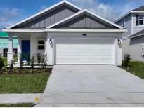 Charming single-story home featuring a wide driveway, a two-car garage, and a vibrant blue front door at 4295 Twisted Twig Bnd, Kissimmee, FL 34746