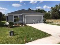 Charming single-Gathering home features a gray exterior, well-manicured lawn, and a paved driveway leading to an attached garage at 4844 Summerfield Cir, Winter Haven, FL 33881