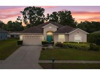 Charming single-story home with a well-manicured lawn, colorful flower beds, and a two-car garage at sunset at 813 Lancer Cir, Ocoee, FL 34761