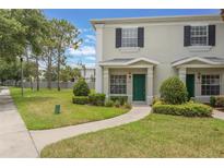 Inviting townhome featuring a well-manicured lawn and charming curb appeal with a green door at 9492 Flowering Cottonwood Rd # 82, Orlando, FL 32832