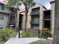Condo building with palm trees, balconies, a red roof, and black metal fencing in a lush green landscape at 199 Afton Sq # 108, Altamonte Springs, FL 32714