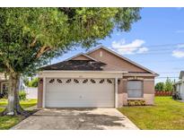 Tan single-Gathering home with a two-car garage and a well-manicured lawn at 2181 Jessa Dr, Kissimmee, FL 34743