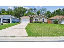 Charming single-story home features a well-maintained lawn, attached garage, and inviting curb appeal at 419 Cierra Oaks Cir, Lady Lake, FL 32159