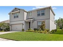Two-story home with a well-manicured lawn, gray siding, and an attached two-car garage provides great curb appeal at 5065 Sparkling Water Way, Kissimmee, FL 34746