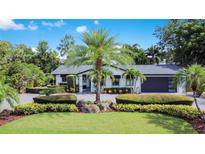 Beautiful single-story home featuring lush landscaping, palm trees, and a circular driveway at 6317 Cheryl St, Orlando, FL 32819