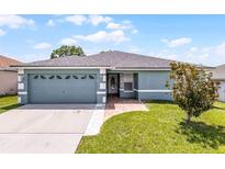 Charming single-story home with a well-manicured lawn, two car garage, and brick walkway at 141 Winsor Ave, Davenport, FL 33837