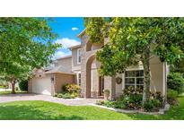 Charming home featuring an arched brick entryway, lush landscaping, and a well-manicured lawn at 14244 Nottingham Way Cir, Orlando, FL 32828
