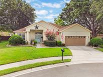 Charming single-story home with a well-manicured lawn, mature trees, and a lovely blue front door at 165 Fig Tree Run, Longwood, FL 32750