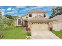 Charming two-story home features a brick facade, well-manicured lawn, and attached two car garage at 1916 Excalibur Dr, Orlando, FL 32822