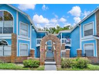 Charming two-story condo with blue exterior, brick accents and well-manicured landscaping under a sunny blue sky at 2739 N Poinciana Blvd # 77, Kissimmee, FL 34746